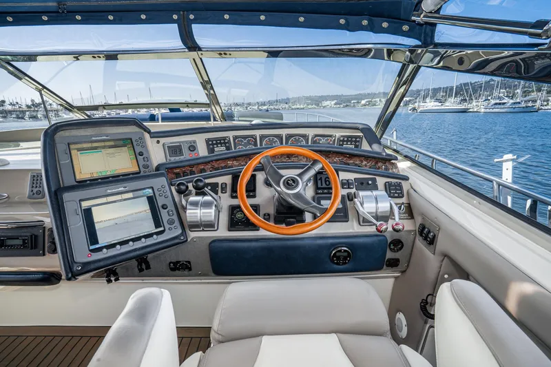 Slide: The Image of 1999 Sea Ray 500 Sundancer helm with navigation screens and steering wheel, overlooking marina. - 11