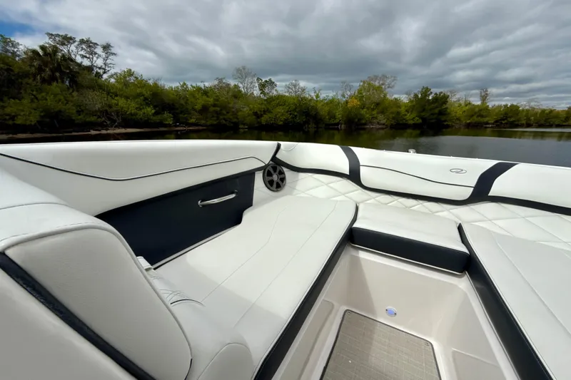 Slide: The Image of 2021 Regal 23 OBX boat interior with white seating, near lush greenery and water. - 6