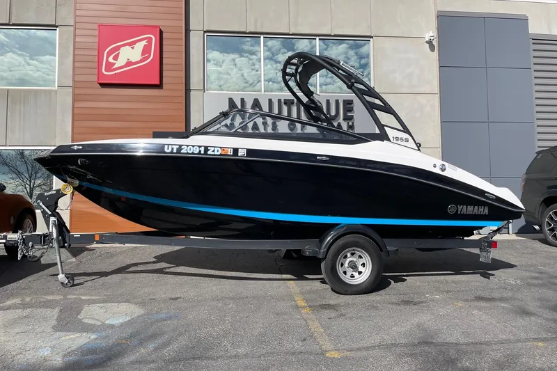 The Image of 2022 Yamaha Boats 195S on trailer outside dealership, side view. - 1
