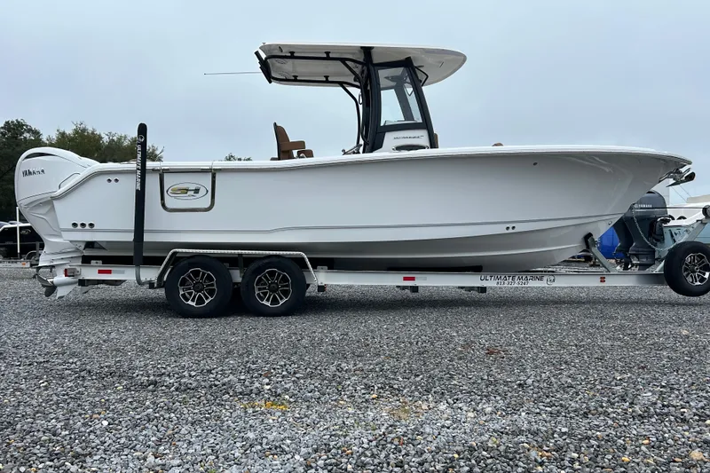 Slide: The Image of 2025 Sea Hunt Ultra 265 SE boat on trailer, side view, parked on gravel. - 6