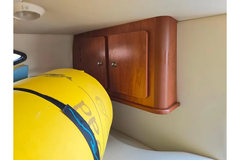Slide: The Image of 2007 Rinker 246 Captiva Cuddy interior with wooden cabinet and yellow inflatable. - 17