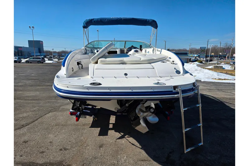 Slide: The Image of 2007 Rinker 246 Captiva Cuddy boat with ladder, parked on asphalt, under clear blue sky. - 2