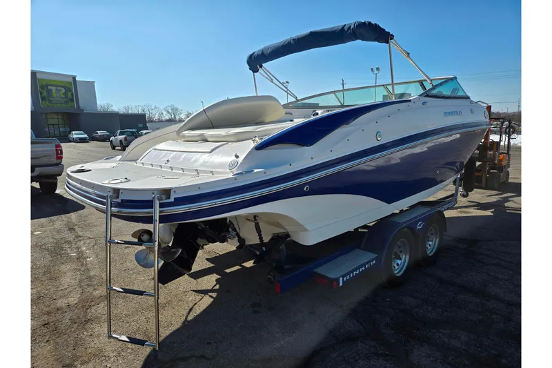 Slide: The Image of 2007 Rinker 246 Captiva Cuddy boat on trailer, blue and white design, sunny day. - 3