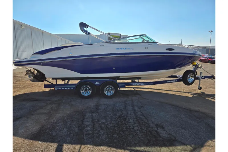 Slide: The Image of 2007 Rinker 246 Captiva Cuddy boat on trailer, blue and white design, parked outdoors. - 4