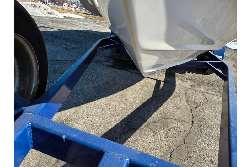 Slide: The Image of 2007 Rinker 246 Captiva Cuddy boat on blue trailer, parked on cracked pavement. - 7