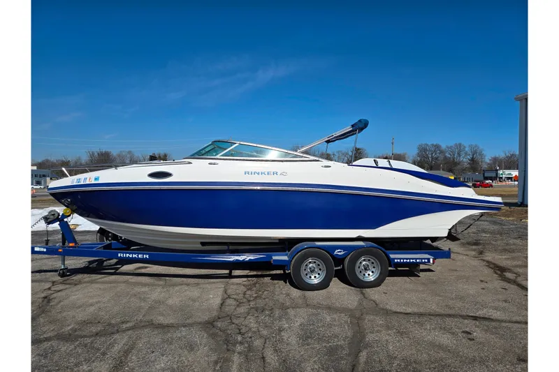 Slide: The Image of 2007 Rinker 246 Captiva Cuddy boat on trailer, blue and white design, parked outdoors. - 9