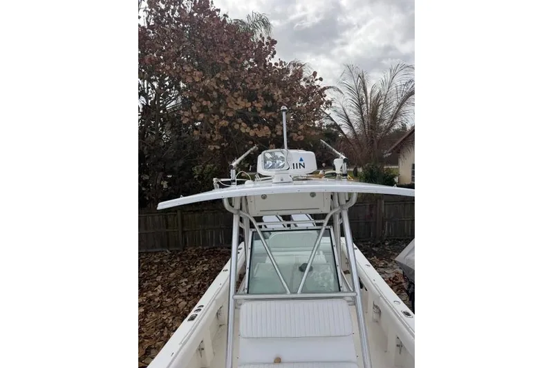 Slide: The Image of 2002 Regulator 26 Forward Seating boat with T-top and radar, parked outdoors. - 19