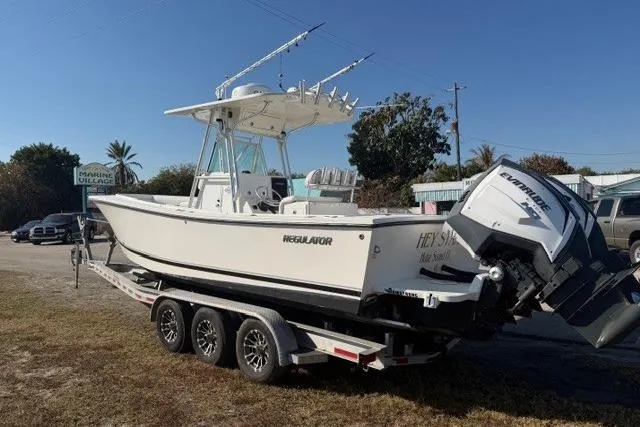Slide: The Image of 2002 Regulator 26 Forward Seating boat on trailer with dual engines, parked outdoors. - 3
