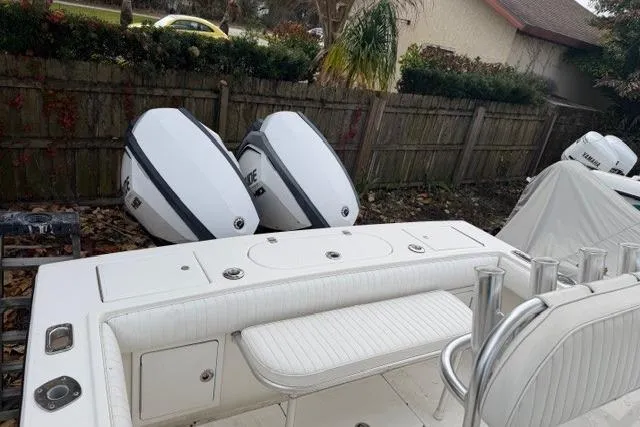Slide: The Image of 2002 Regulator 26 Forward Seating boat with dual outboard engines, parked outdoors. - 8