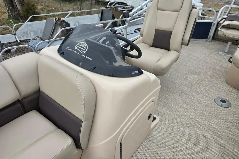 Slide: The Image of 2019 Sun Tracker Party Barge 22 Sport Fish interior with beige seating and steering console. - 10