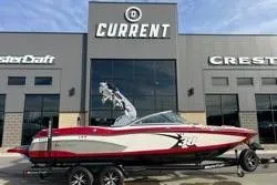 The Image of 2013 MasterCraft X30 boat displayed outside dealership with "Current" signage. - 1