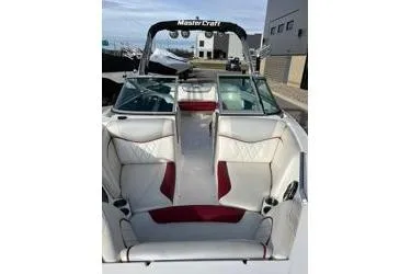Slide: The Image of 2013 MasterCraft X30 boat with white and red interior, docked near buildings. - 8