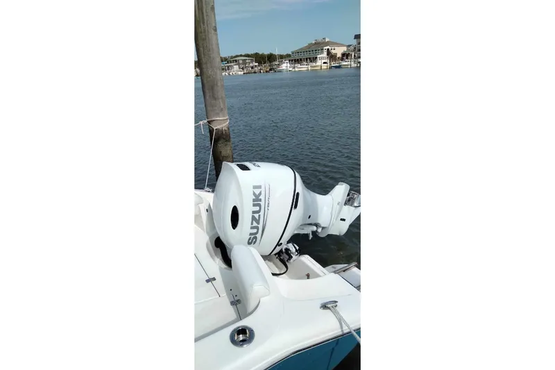 Slide: The Image of 2022 Bulls Bay 230 Center Console with Suzuki outboard motor docked by the water. - 2