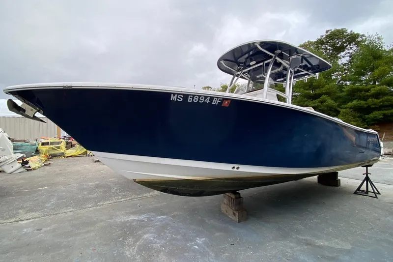 The Image of 2015 Sportsman Heritage 251 Center Console boat on dry dock, blue hull, overcast sky. - 0