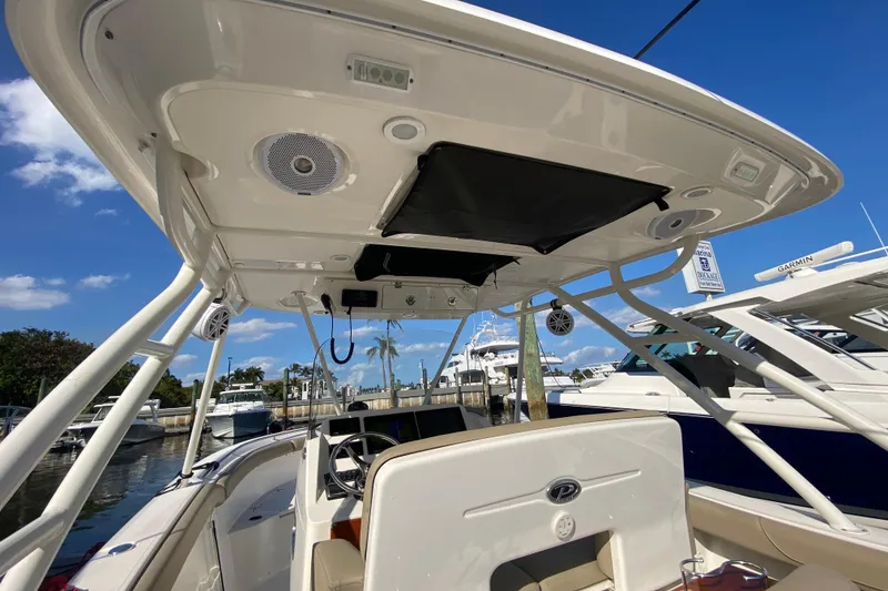 Slide: The Image of 2015 Pursuit S 280 Sport boat interior with canopy and docked yachts in background. - 10