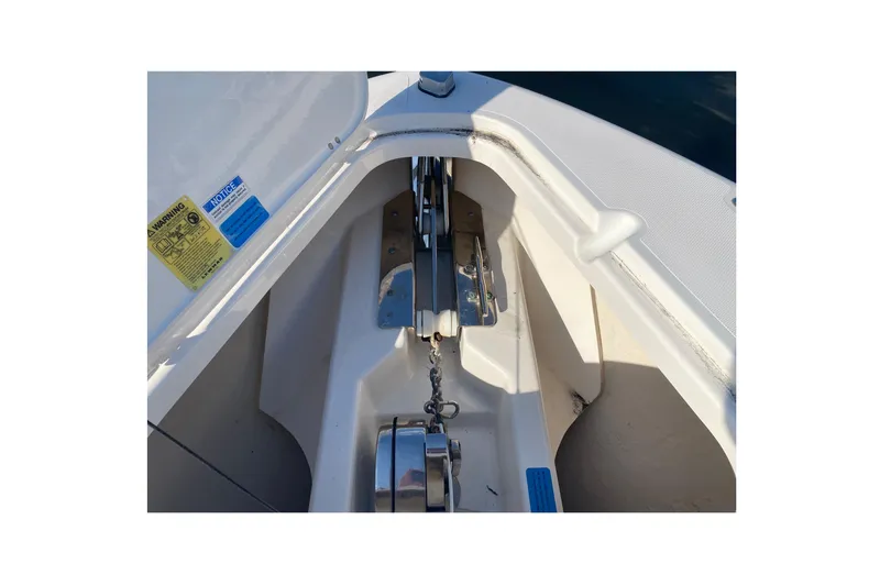 Slide: The Image of 2015 Pursuit S 280 Sport boat anchor compartment with visible chain and warning labels. - 24