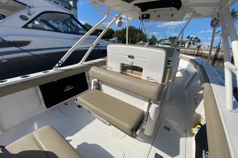 Slide: The Image of 2015 Pursuit S 280 Sport boat interior with seating and helm, docked near other boats. - 8