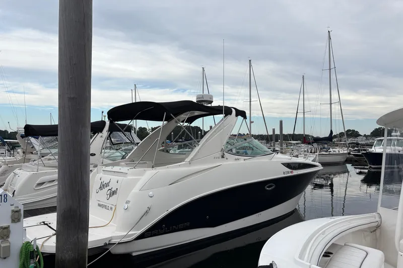 The Image of 2011 Bayliner 285 Cruiser docked at marina, surrounded by sailboats under cloudy sky. - 1