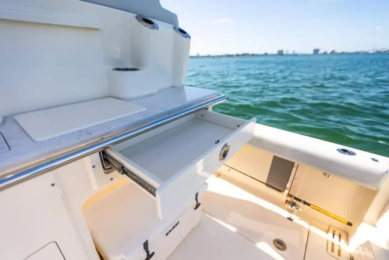 Slide: The Image of Manufacturer Provided Image: 2025 Scout 260 LXF boat interior with open storage drawer, ocean view. - 7