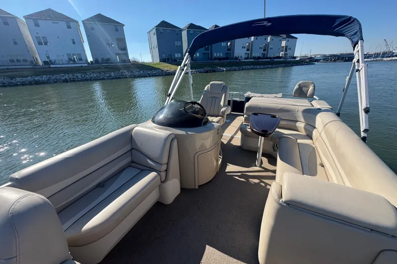 Slide: The Image of 2012 Bennington 2275 GFS pontoon boat with beige seating, docked near waterfront homes. - 16