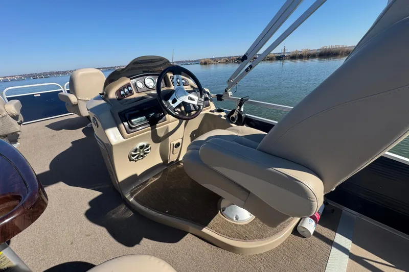 Slide: The Image of 2012 Bennington 2275 GFS boat interior with steering wheel, beige seating, and lake view. - 27