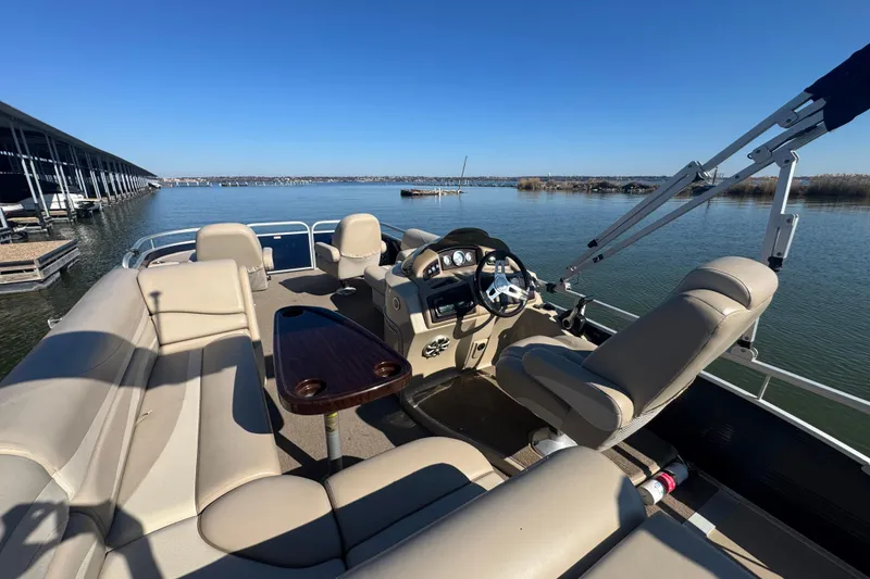Slide: The Image of 2012 Bennington 2275 GFS pontoon boat interior with seating and steering console on a calm lake. - 28
