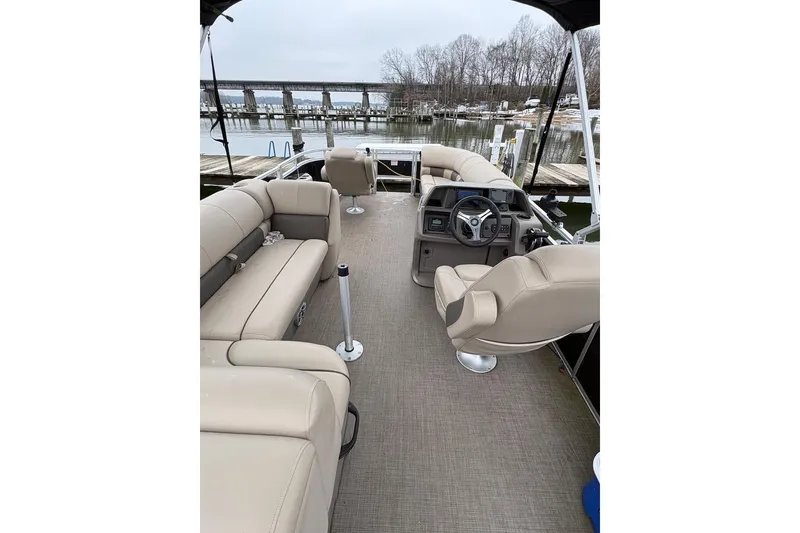 Slide: The Image of 2024 Sun Tracker SportFish 20 DLX pontoon boat interior with beige seating and steering console. - 4