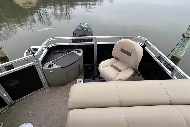 Slide: The Image of 2024 Sun Tracker SportFish 20 DLX pontoon boat interior with seating and motor view. - 5