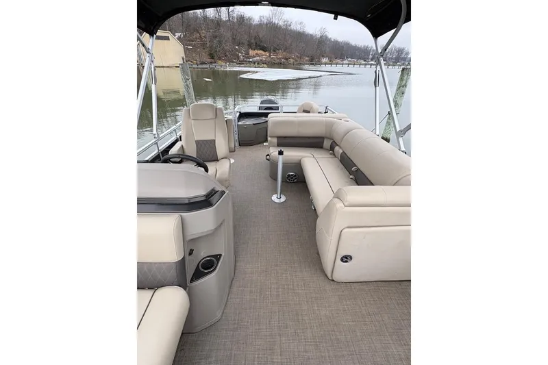 Slide: The Image of 2024 Sun Tracker SportFish 20 DLX pontoon boat interior with beige seating and lake view. - 7