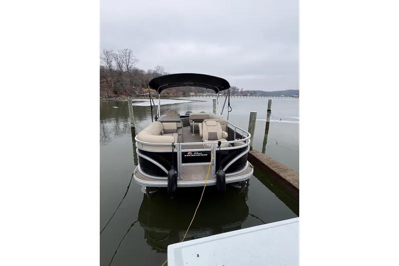 Slide: The Image of 2024 Sun Tracker SportFish 20 DLX pontoon boat docked on a calm lake. - 8