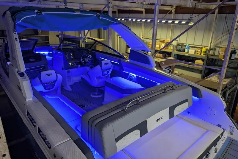 Slide: The Image of 2024 Chaparral 267 SSX boat interior with blue LED lighting in a warehouse setting. - 30