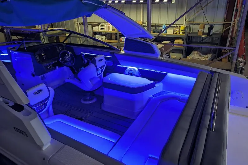 Slide: The Image of 2024 Chaparral 267 SSX boat interior with blue LED lighting in a warehouse setting. - 32