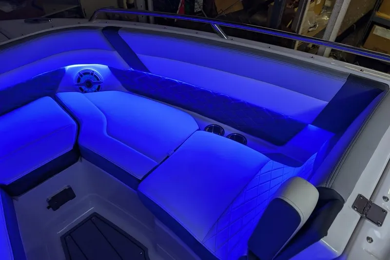 Slide: The Image of 2024 Chaparral 267 SSX boat interior with blue LED lighting and cushioned seating. - 38