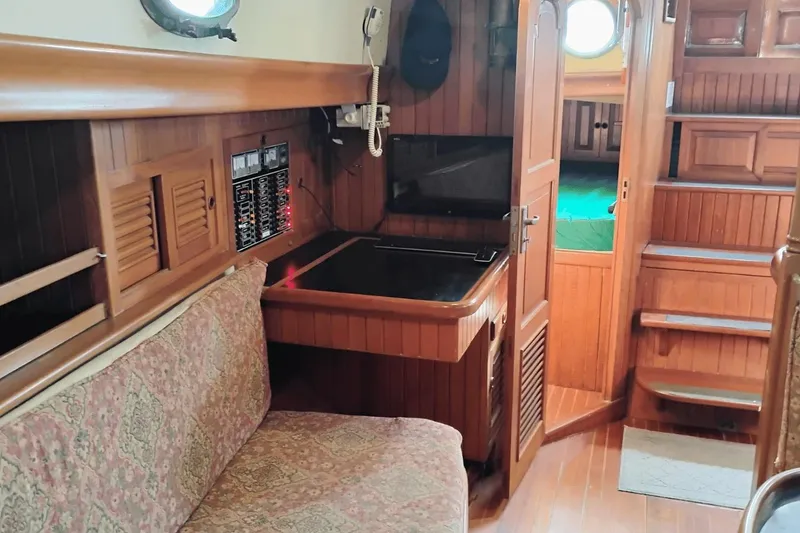 Slide: The Image of 1985 Hans Christian 38 yacht interior with wooden paneling and cozy seating area. - 11