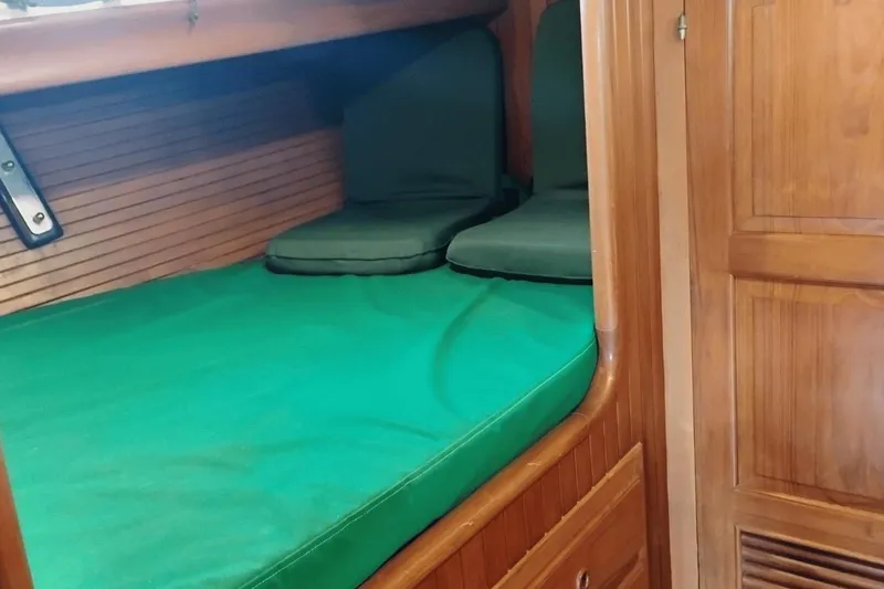 Slide: The Image of 1985 Hans Christian 38 sailboat cabin with green bedding and wooden interior. - 17