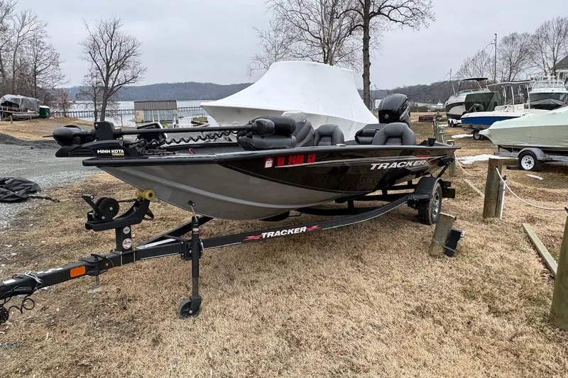Slide: The Image of 2023 Tracker Pro Team 175 TXW boat on trailer, parked outdoors near a lake. - 2