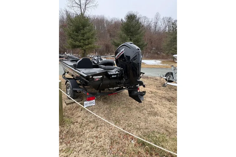Slide: The Image of 2023 Tracker Pro Team 175 TXW boat with Mercury engine, parked on grass. - 3