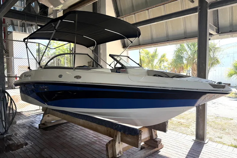 The Image of 2021 Campion Chase 20 boat with canopy, displayed on a wooden stand indoors. - 0