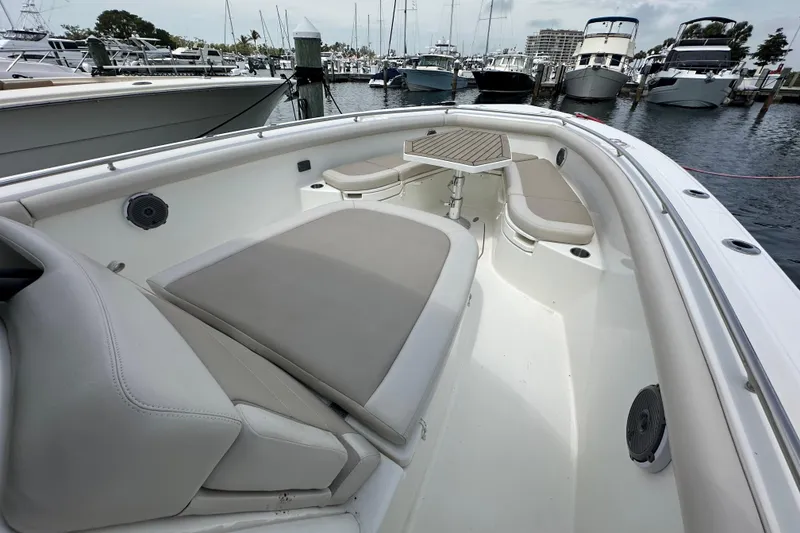Slide: The Image of 2018 Boston Whaler 350 Outrage boat interior with cushioned seating and table at marina. - 18