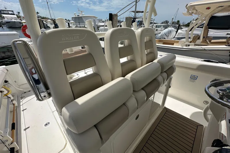 Slide: The Image of 2018 Boston Whaler 350 Outrage boat interior with cushioned seating and steering wheel. - 23