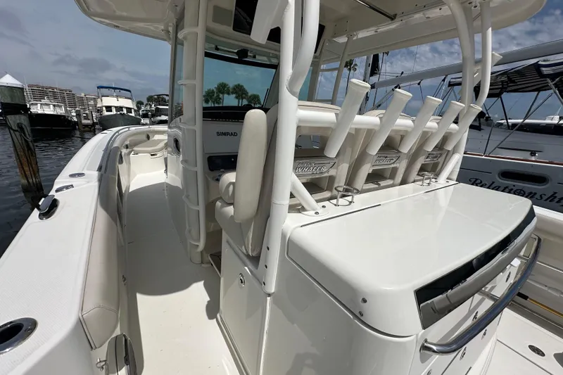 Slide: The Image of 2018 Boston Whaler 350 Outrage boat docked, featuring rod holders and helm station. - 31