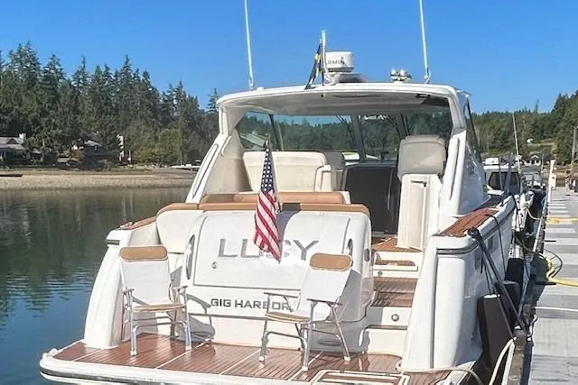 Slide: The Image of 2008 Tiara Yachts 3900 Sovran docked, rear view with American flag, serene waterfront setting. - 2