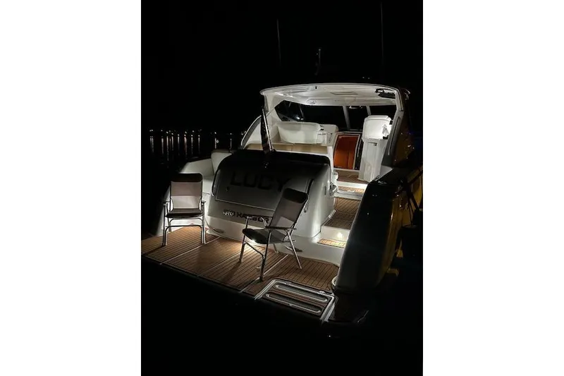 Slide: The Image of 2008 Tiara Yachts 3900 Sovran illuminated at night, featuring deck chairs and ambient lighting. - 4