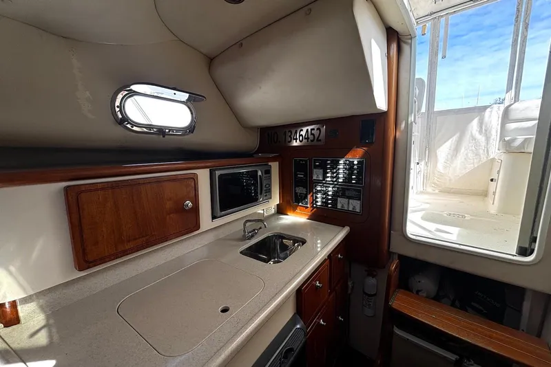 Slide: The Image of 2006 Pursuit 3070 Offshore boat interior with kitchenette, sink, and microwave. - 16