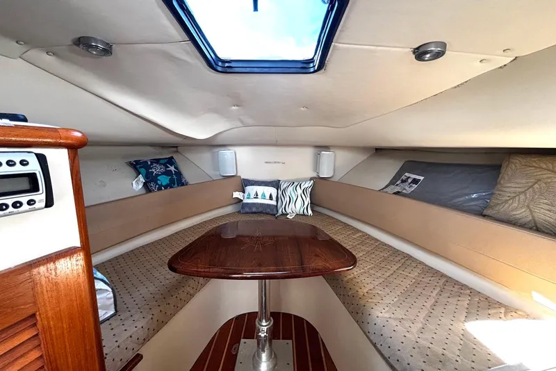 Slide: The Image of 2006 Pursuit 3070 Offshore cabin interior with skylight, cushions, and wooden table. - 17
