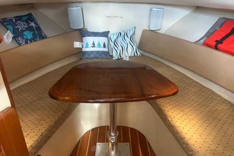 Slide: The Image of 2006 Pursuit 3070 Offshore cabin interior with cushions and wooden table. - 18