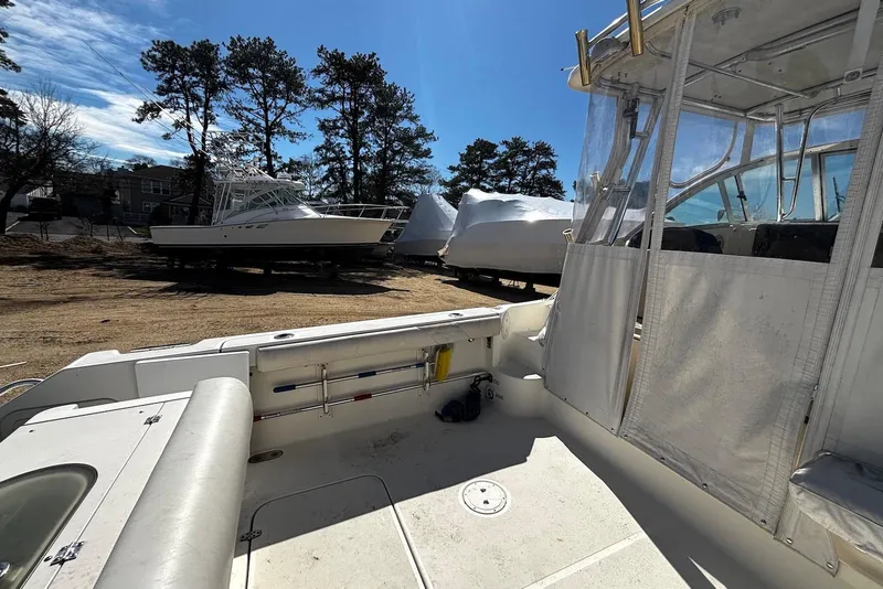 Slide: The Image of 2006 Pursuit 3070 Offshore boat docked, surrounded by trees and other boats. - 21