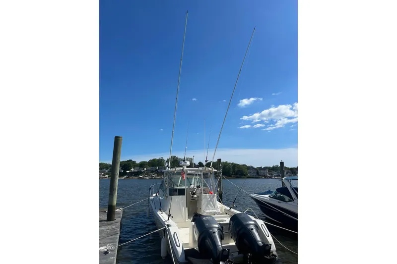 Slide: The Image of 2006 Pursuit 3070 Offshore boat docked with dual engines under a clear blue sky. - 5