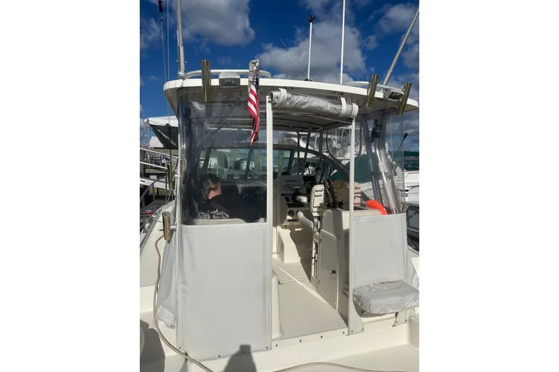 Slide: The Image of 2006 Pursuit 3070 Offshore boat with clear enclosure and American flag, docked under blue sky. - 8