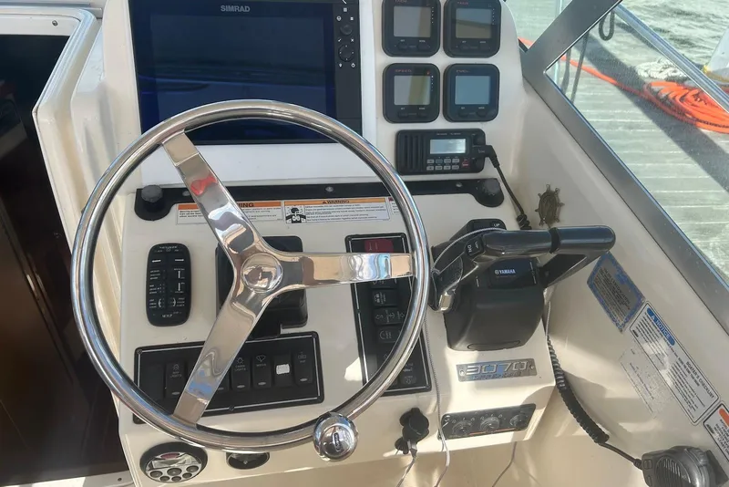 Slide: The Image of Control panel of a 2006 Pursuit 3070 Offshore boat with steering wheel and instruments. - 9